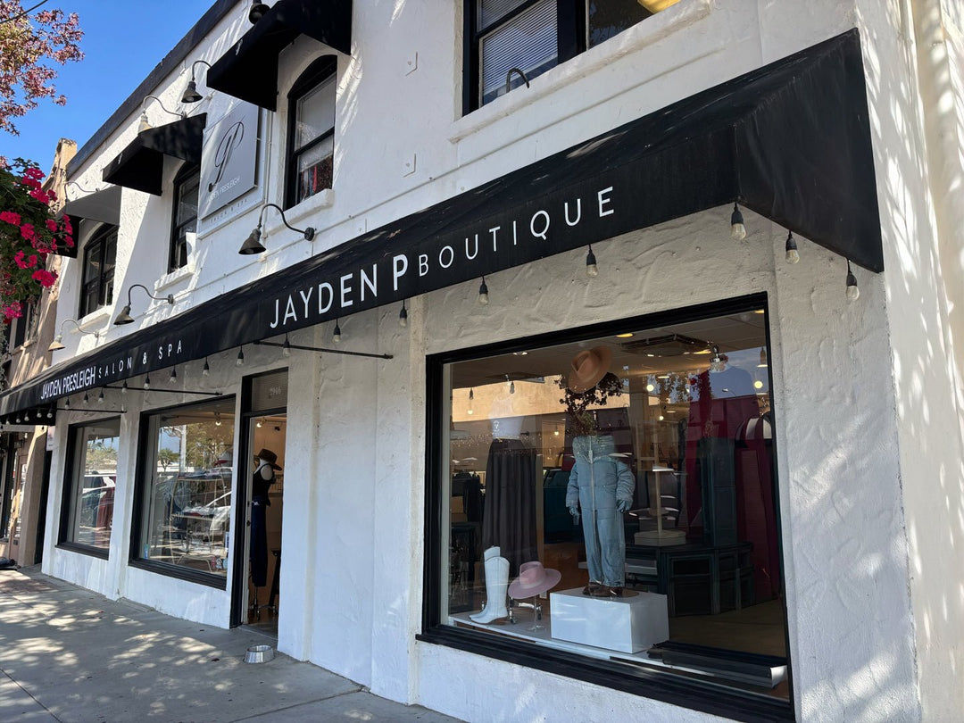 Jayden P Boutique storefront in Carlsbad, with a black awning and clothing displayed in the window.
