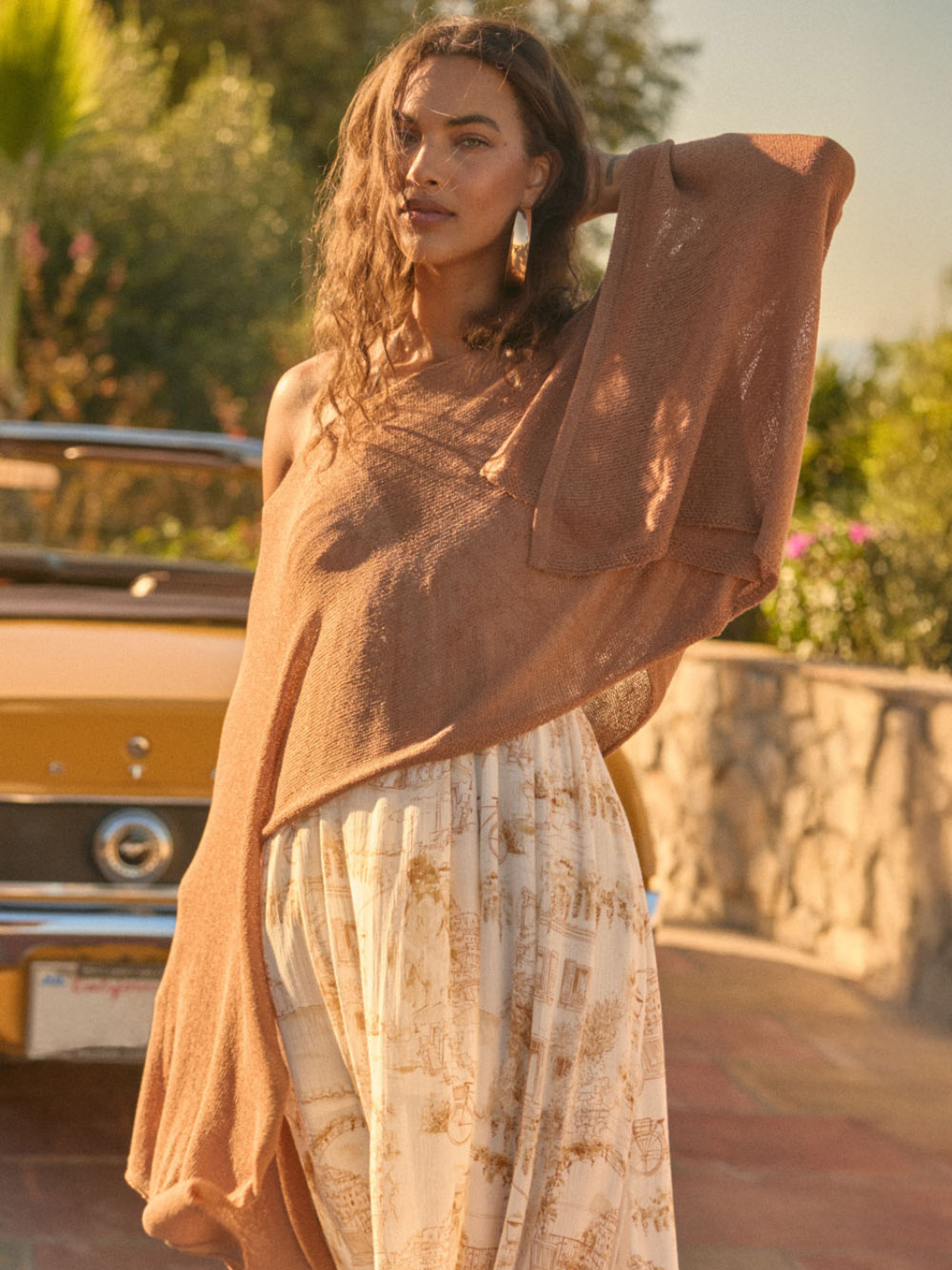 Daydrift Sheer Knit Poncho Sweater in tan, oversized, airy draped poncho worn outdoors beside a vintage yellow car.