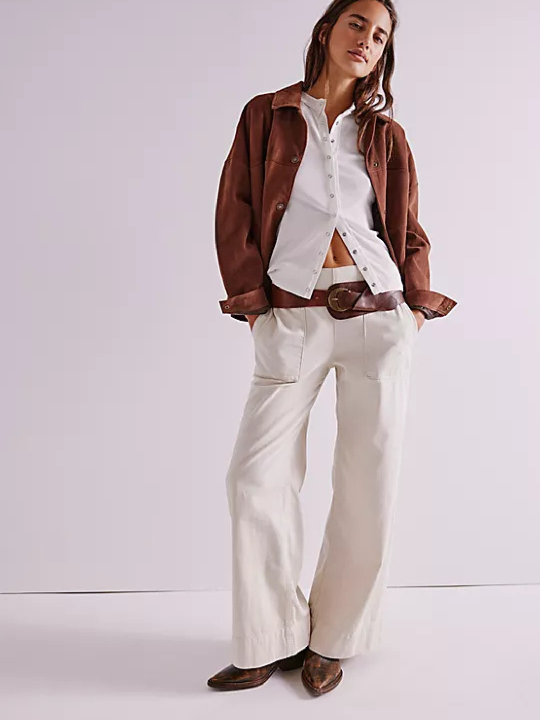 Model wearing Free People We The Free Breezy Denim Pull-On Jeans with white button-down, brown belt and jacket