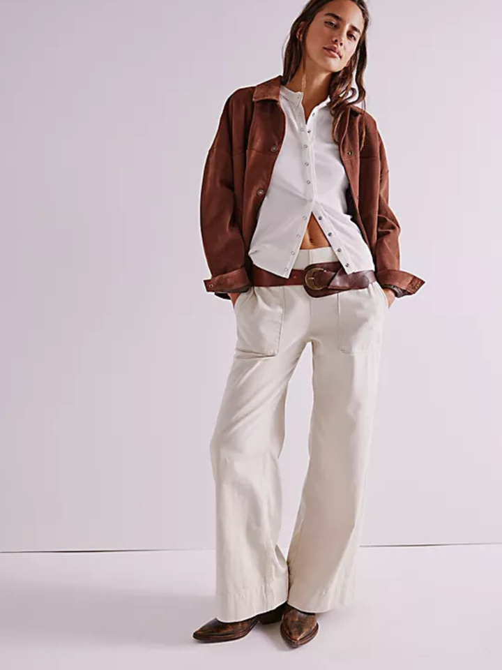Model wearing Free People We The Free Breezy Denim Pull-On Jeans with white button-down, brown belt and jacket