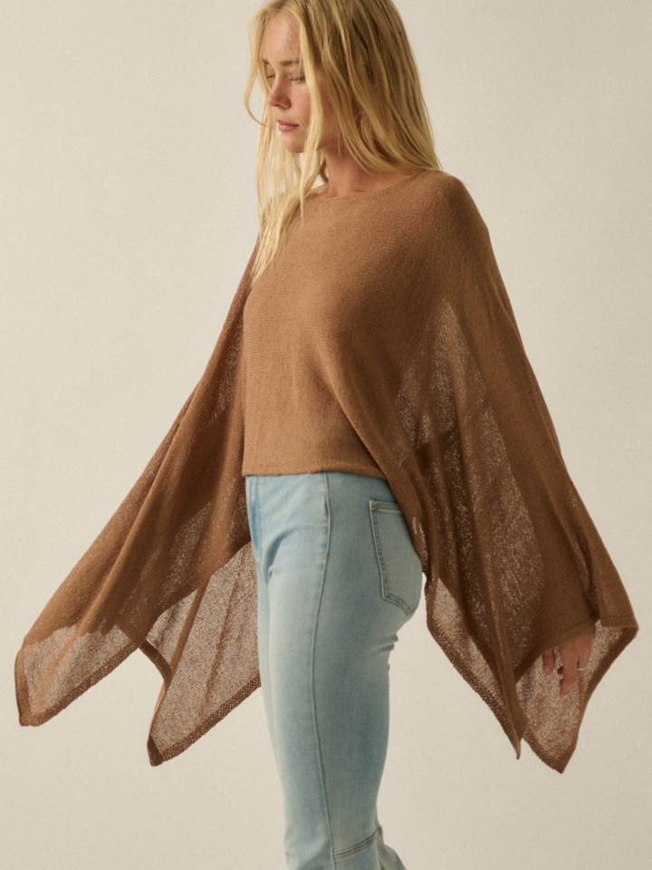 Daydrift Sheer Knit Poncho Sweater in camel, oversized and airy with a cloudlike drape over light-blue jeans.