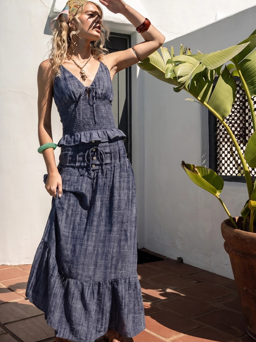 Woman wearing Indigo Dreams high-waist smocked denim maxi skirt with tiered ruffle hem and drawstring detail.