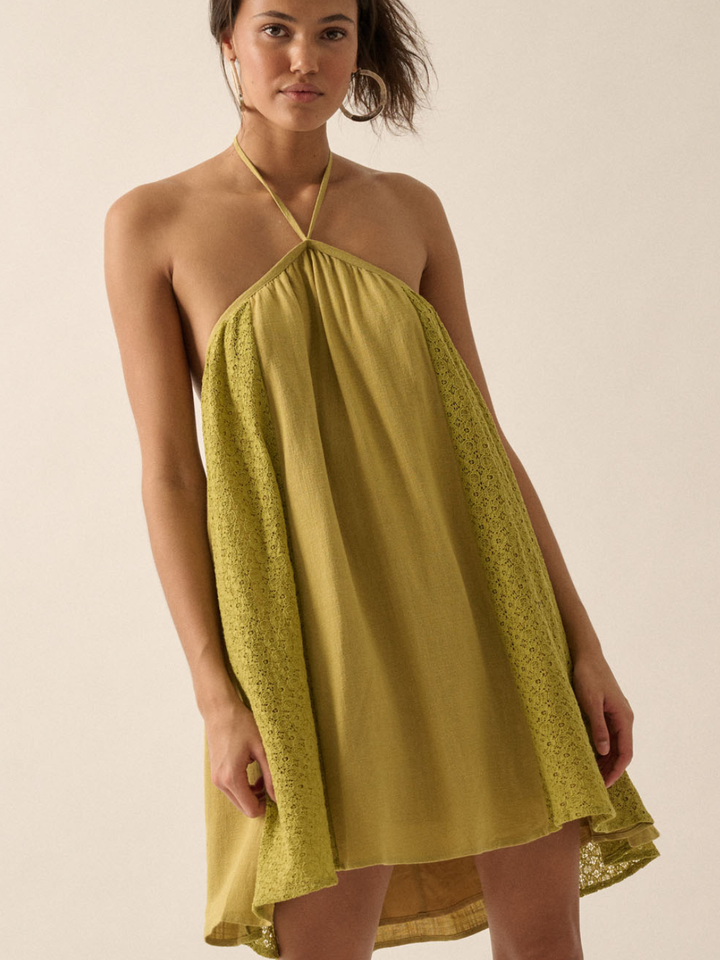 Citrine lace open-back halter mini dress with floral lace panels worn by model.