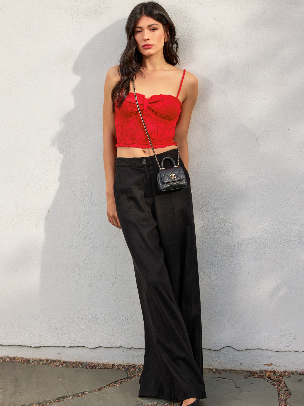 Fashionable woman wearing the Amorette Smocked Sweetheart Crop Top, showcasing its ruffled hem and flirty style.