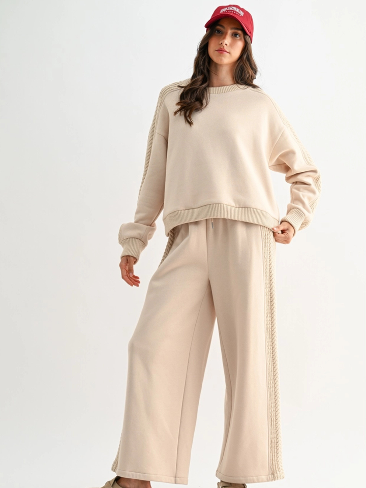The Aria Cable Knit Sweatshirt in beige with matching wide-leg pants and cable-knit detailing on sleeves and sides.
