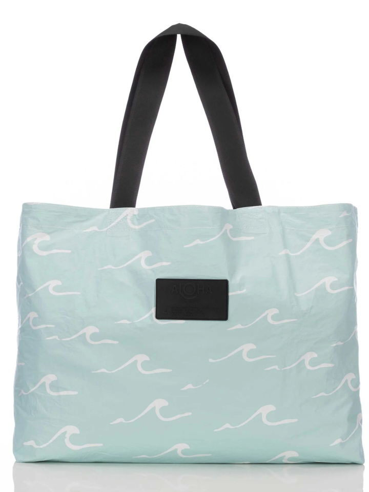 Seaside bag from ALOHA COLLECTION in light aqua with white wave pattern, black handles, ALOHA label.