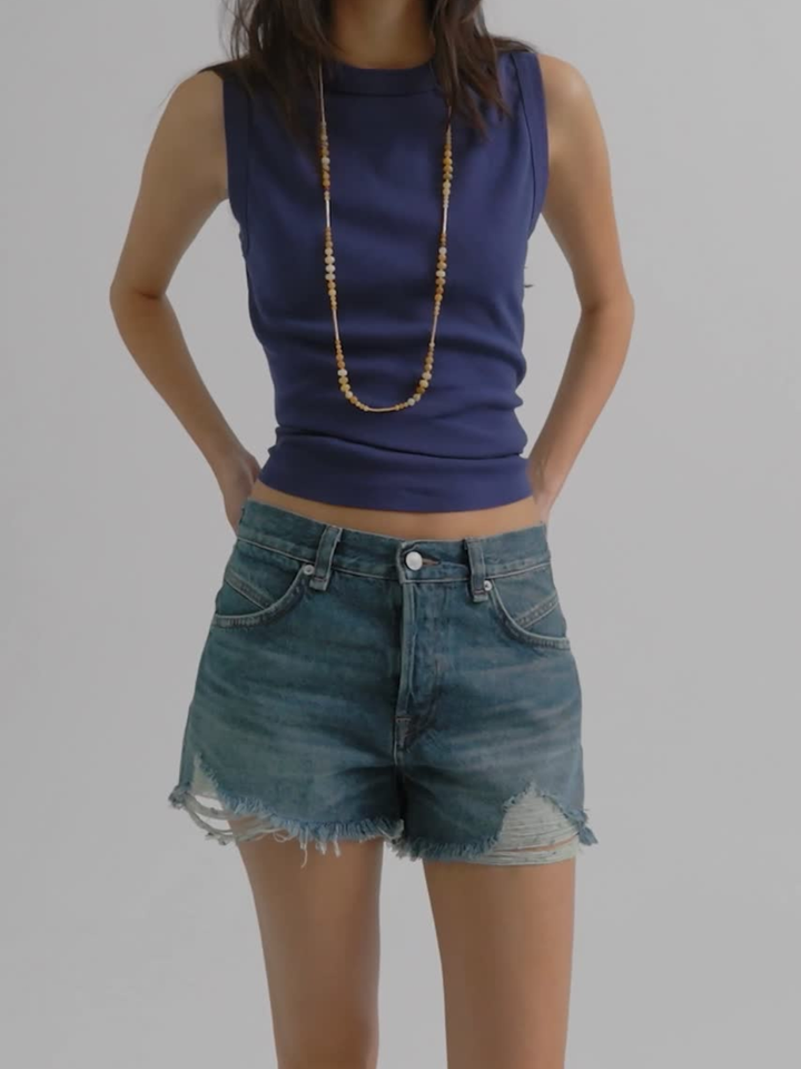 Free People Now Or Never Denim Shorts with distressed hems, worn by a model in a blue sleeveless top.
