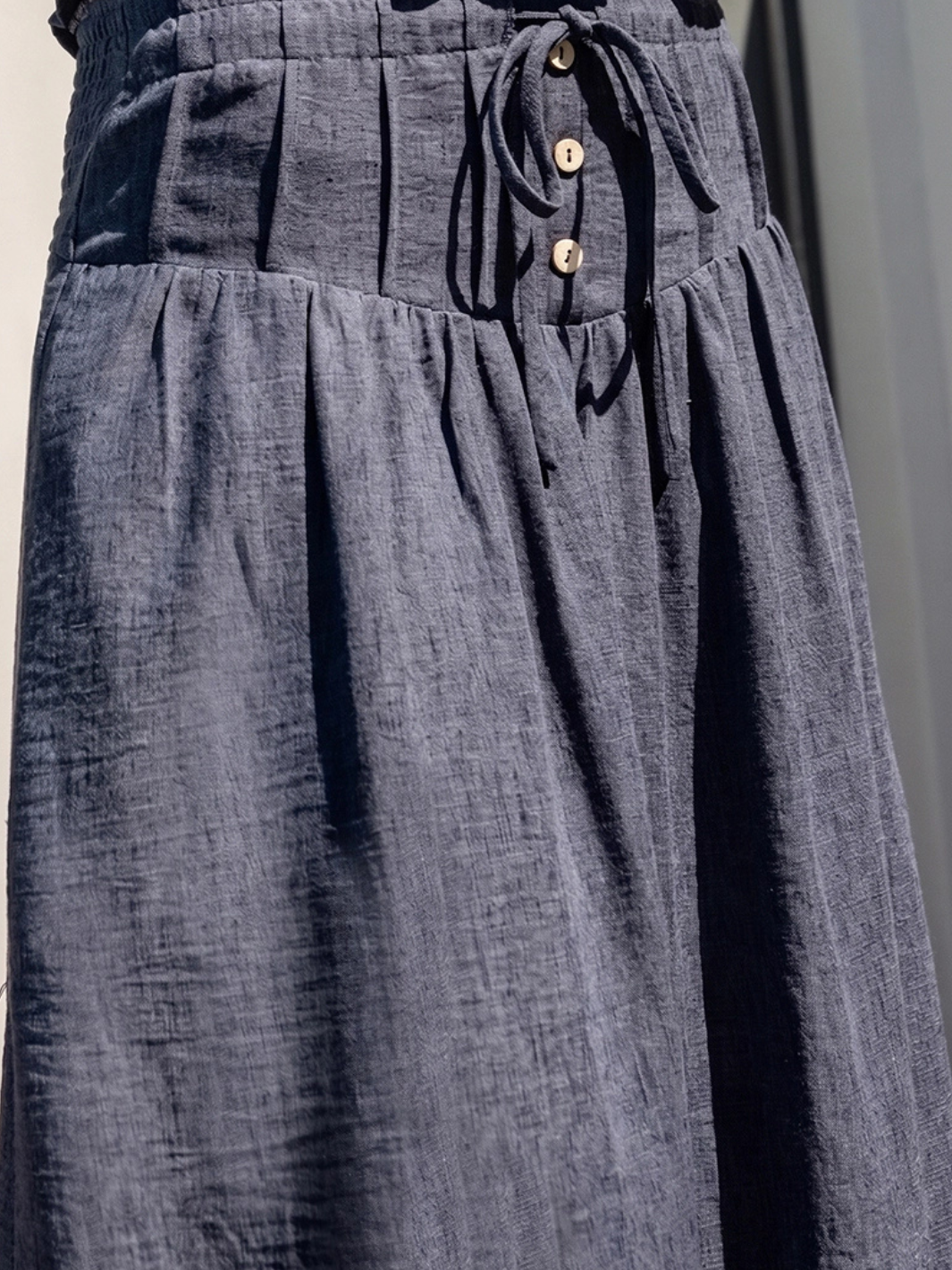 The Indigo Dreams Halter Smocked Denim Top with tie-front, fitted smocked bodice, and wooden buttons in indigo denim.