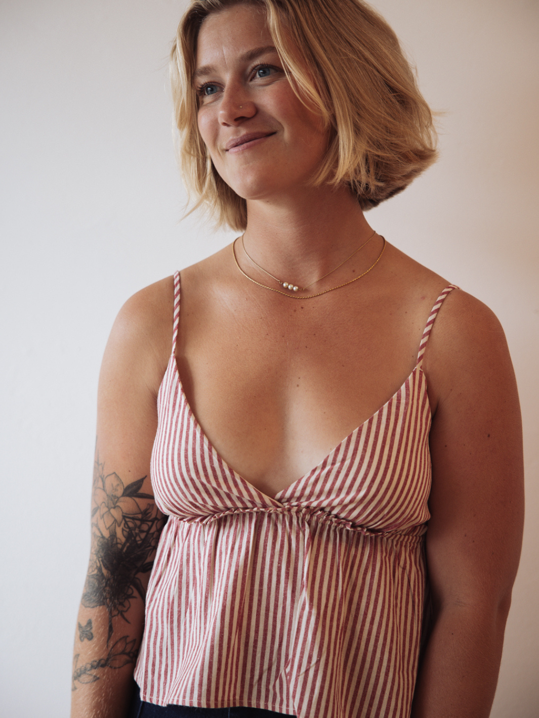 Woman wearing The Sundrop Red Stripe Cotton Babydoll Tank Top with peplum and thin straps.