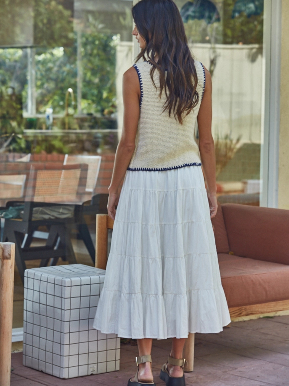 Back view of a model in Coastal Dream Tiered Ruffle Midi Skirt, white, outdoor garden-party setting.