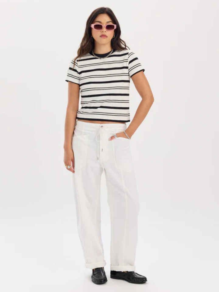 Model wearing white Daze Denim Villa Drawstring Barrel Leg Pant with striped top and black loafers.
