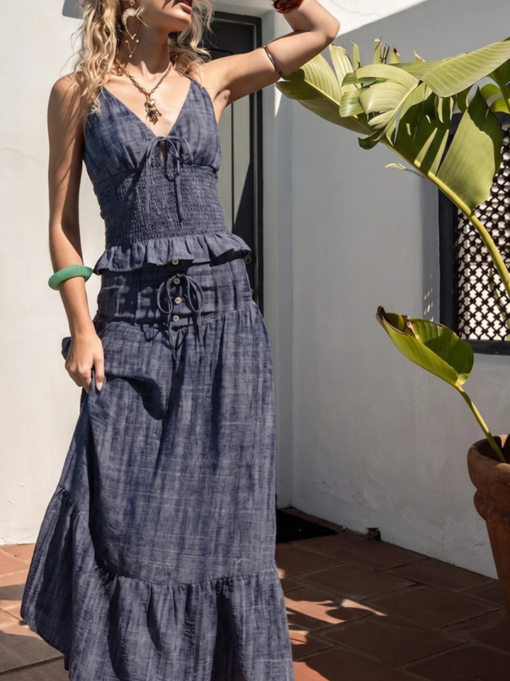 The Indigo Dreams Halter Smocked Denim Top with tie-front, smocked bodice, beaded tassel trim on a model.