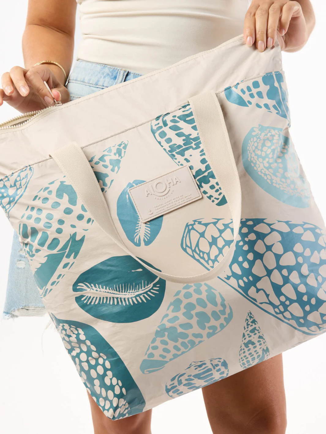 ALOHA Collection Shoreline Bag Collection tote with teal seashell print on cream fabric and beige handles.