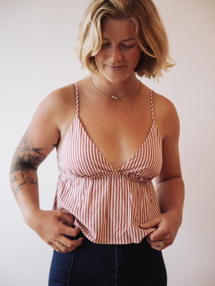 Woman wearing red and white striped cotton babydoll tank top with a peplum waist and thin straps.