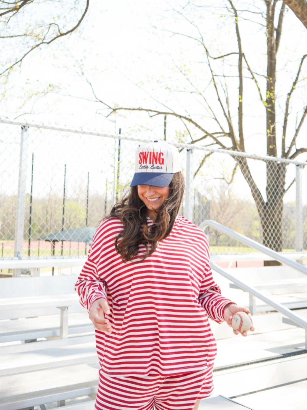 KENZKUSTOMZ Swing Batter Batter Pinstripe Baseball Cap on a smiling woman wearing a red-and-white striped outfit outdoors.