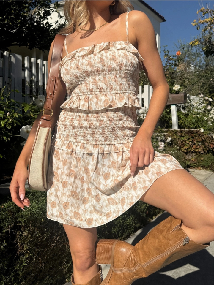 Wildflower Smocked Ruffle Mini Dress in cream floral print with tiered ruffles, worn with tan bag and boots.