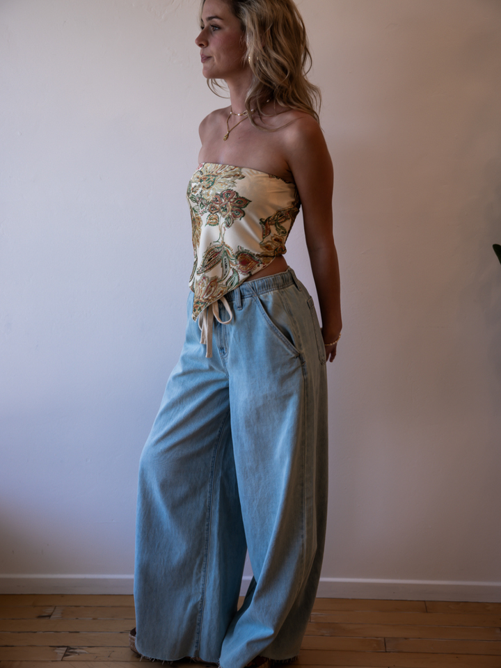 Daze Denim Cabana Wide Leg Pull-On Jeans in light wash worn by a model in a floral strapless top.