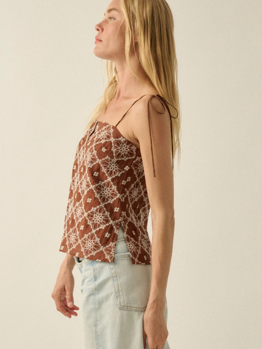 Florentine embroidered tie-strap cami in rust brown with white floral lattice pattern on a model in light jeans.