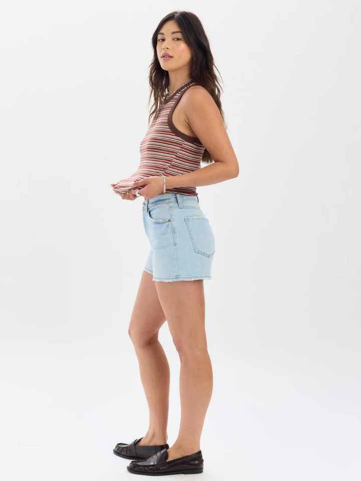 Model wearing DAZE DENIM Troublemaker High Rise Denim Shorts, striped sleeveless top, black loafers.
