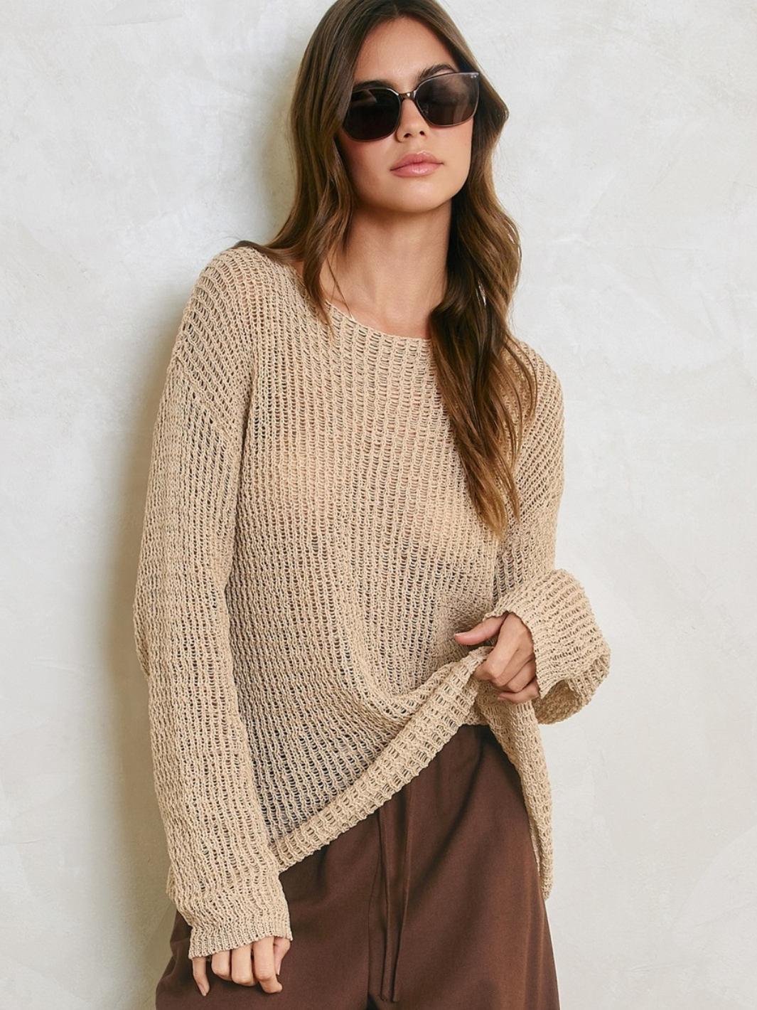 Female model wearing Sandcastle Open-Knit Pullover Sweater in natural taupe with brown pants.