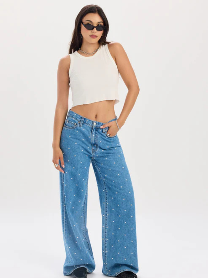 Model wearing Daze Denim The Wanderer mid-rise palazzo jeans in blue with white dot pattern, wide-leg silhouette.