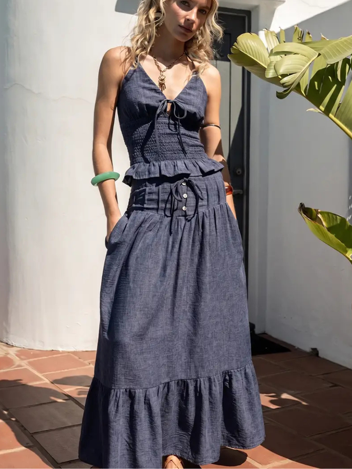 Indigo Dreams halter smocked denim top with tie-front, fitted smocked bodice and ruffled hem.