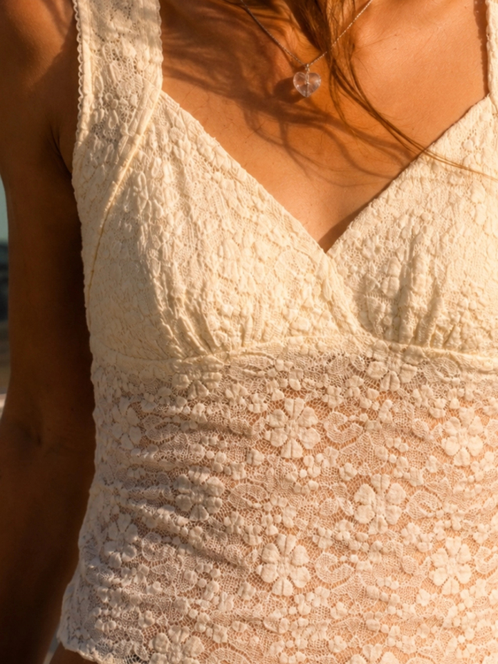 The Noir Floral Lace Cropped Tank Top in cream lace with a V-neck and semi-sheer floral pattern.