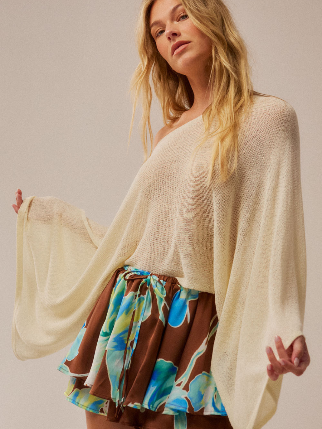 Daydrift Sheer Knit Poncho Sweater in ivory, oversized, airy, featherweight drape on model with colorful skirt