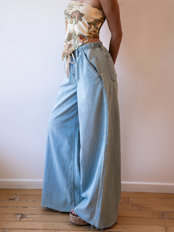 Daze Denim Cabana Wide Leg Pull On Jeans in light wash with a relaxed fit and drawstring waist on a model.