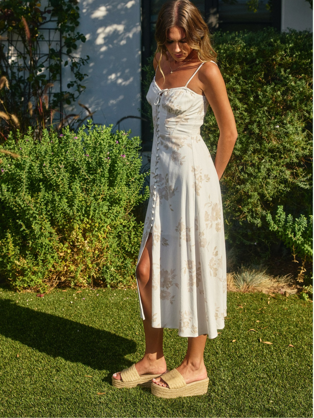 The Garden Party Floral Corset Midi Dress on a model; cream floral print, corset bodice, spaghetti straps, A-line midi.
