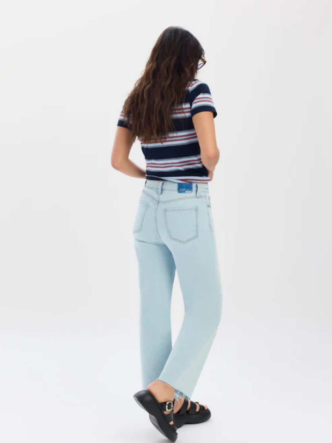 Back view of a model wearing Daze Denim Pleaser high-rise wide-ankle jeans in light indigo wash.