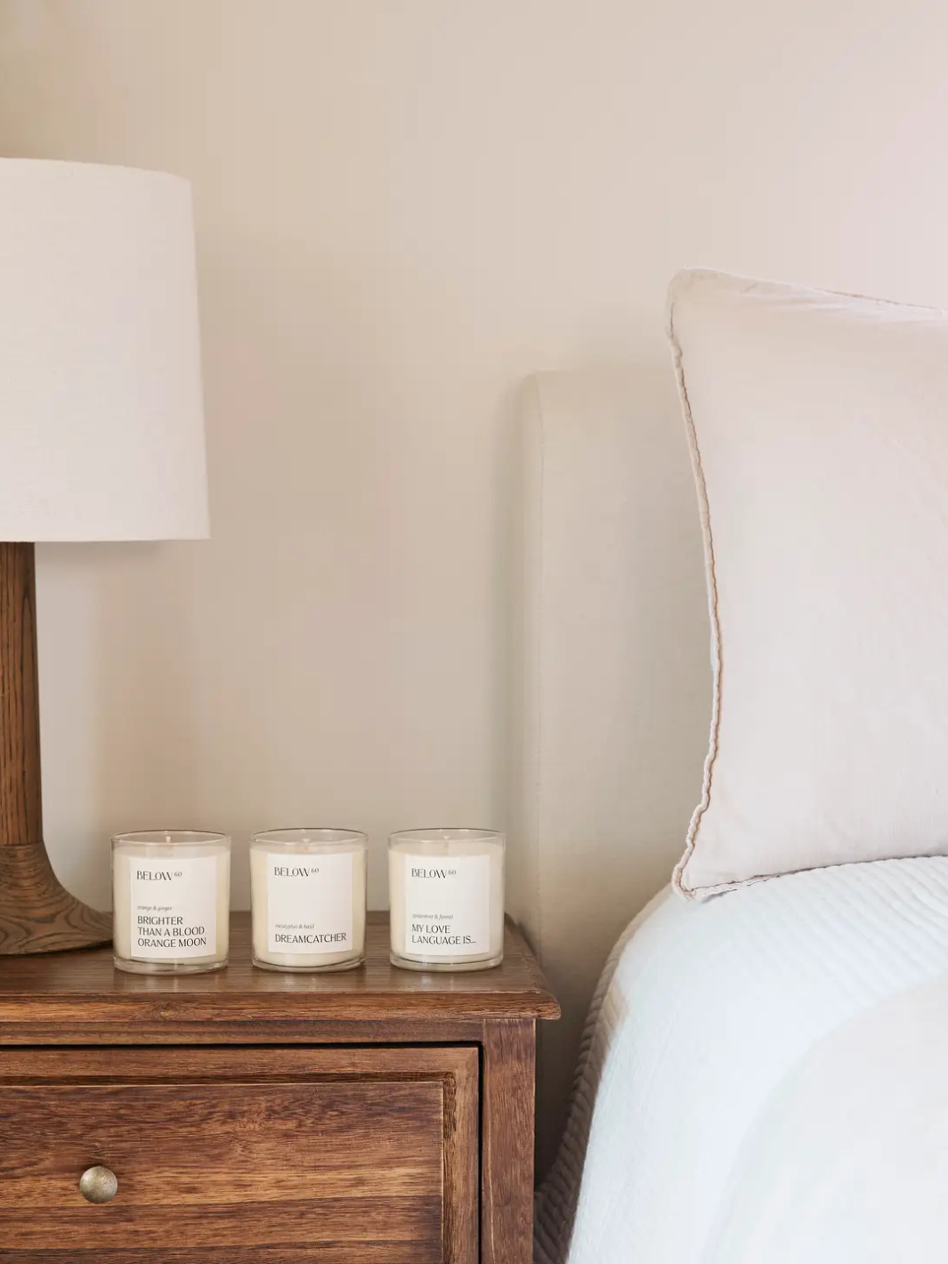 BELOW 60- Brighter Than A Blood Orange Moon candle on a bedside table with other BELOW 60 candles.