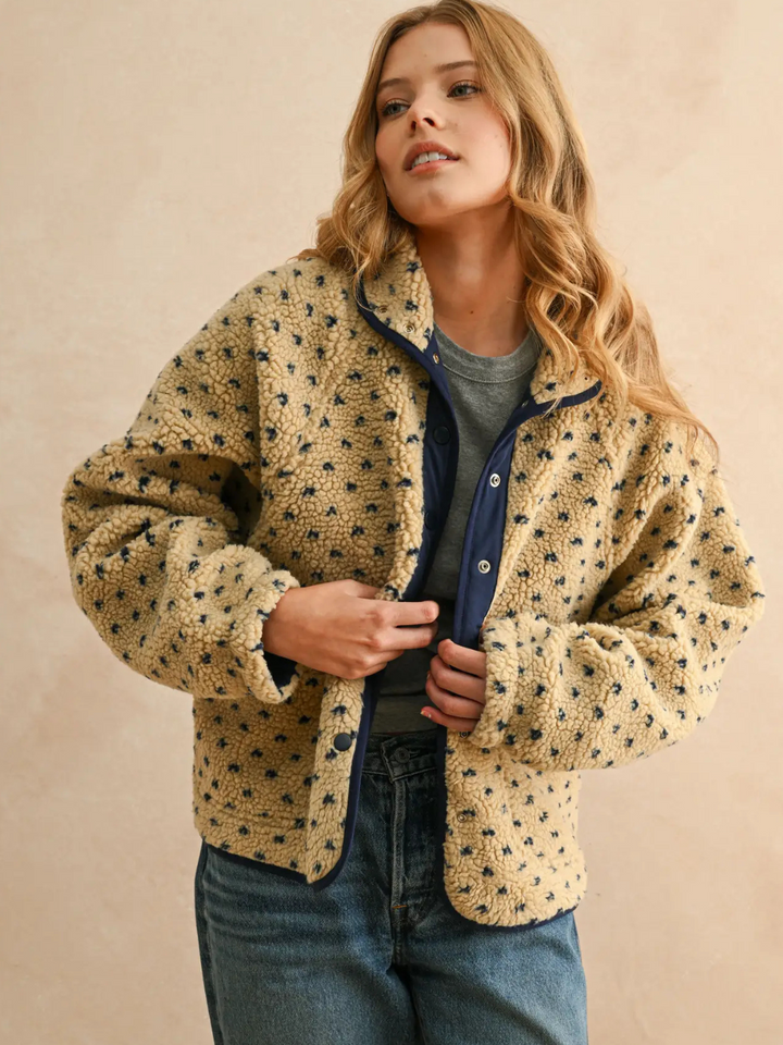 Woman in Canyon Bloom patterned sherpa fleece jacket with beige plush fleece, navy trim, and floral dot pattern.