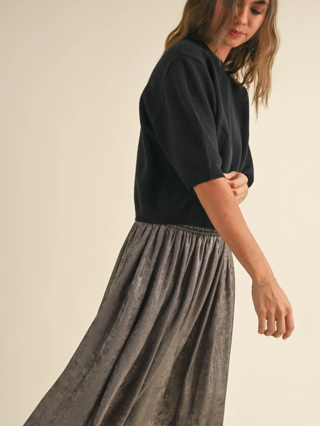 Cleo ribbed knit half-length sleeve sweater top in black, worn with a metallic gray skirt.