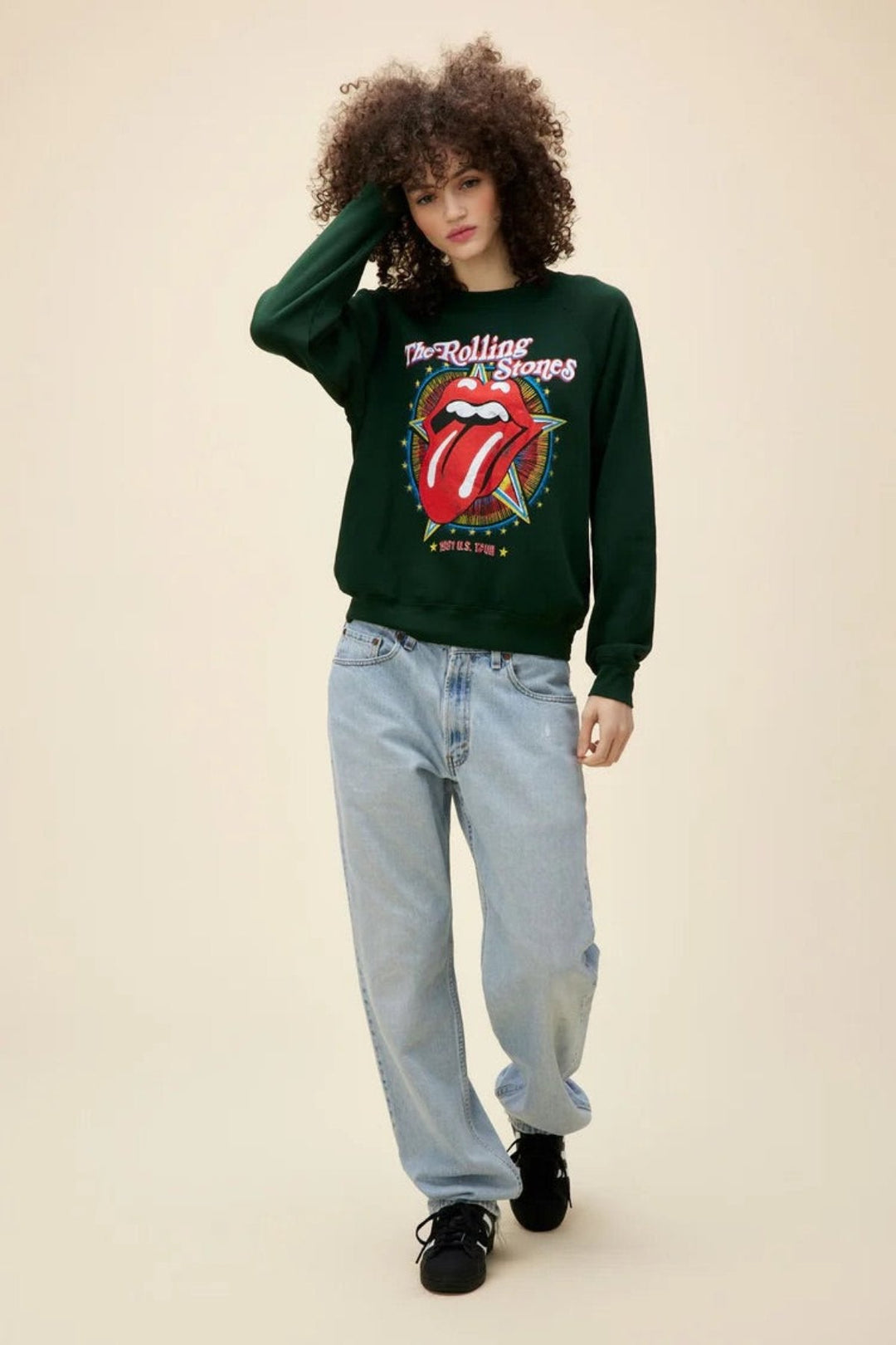 Person wearing a Rolling Stones sweatshirt with iconic tongue logo, paired with light blue jeans.