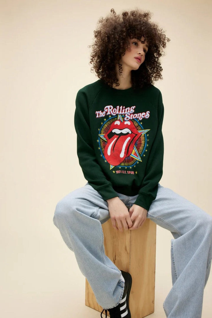 Person wearing a Rolling Stones sweatshirt with iconic tongue logo, paired with light blue jeans.