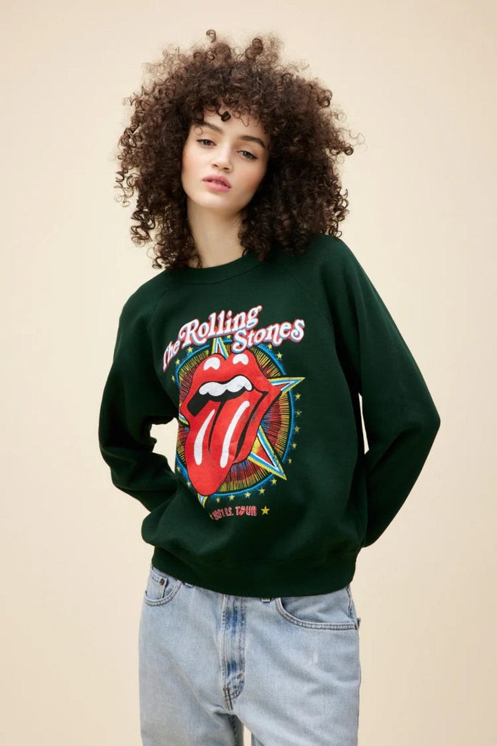 Person wearing a Rolling Stones sweatshirt with iconic tongue logo, paired with light blue jeans.