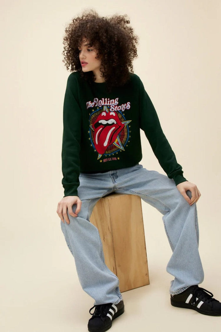 Person wearing a Rolling Stones sweatshirt with iconic tongue logo, paired with light blue jeans.