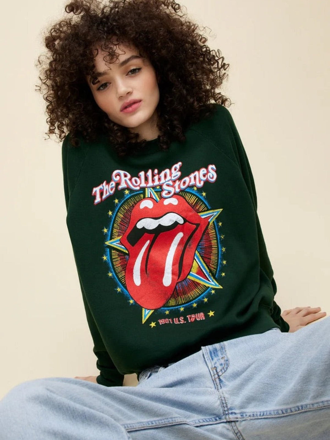 Person wearing a Rolling Stones sweatshirt with iconic tongue logo, paired with light blue jeans.