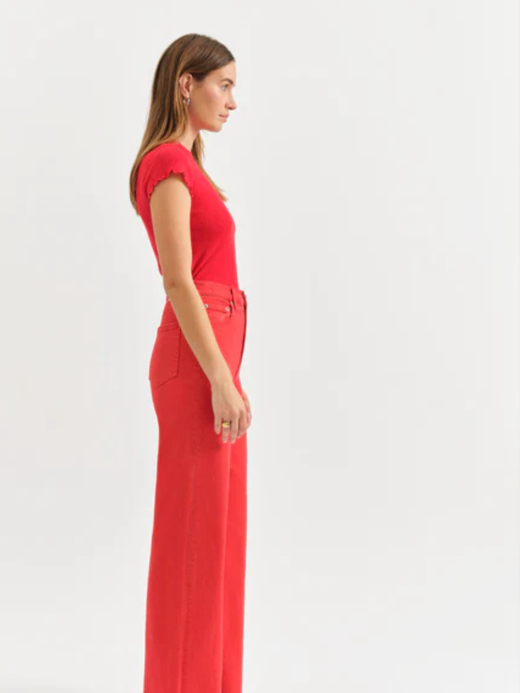 Model wearing red Far Out High Rise Wide Leg Jeans by Daze Denim, side profile.