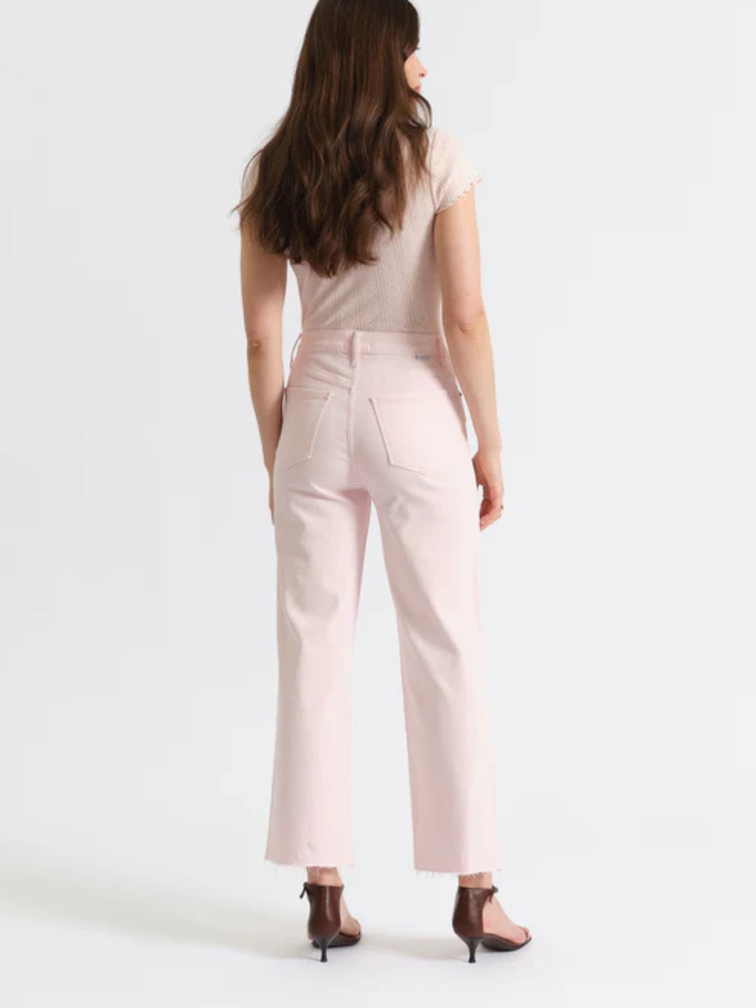 Back view of blush pink DAZE DENIM Pleaser high-rise, wide-ankle jeans with back pockets and raw hem.