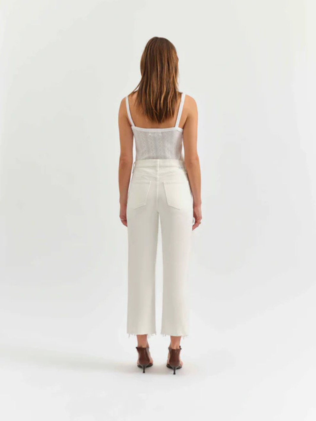 Back view of a model in white Sundaze Swan high-rise vintage straight jeans, cropped ankle-length with frayed hems.