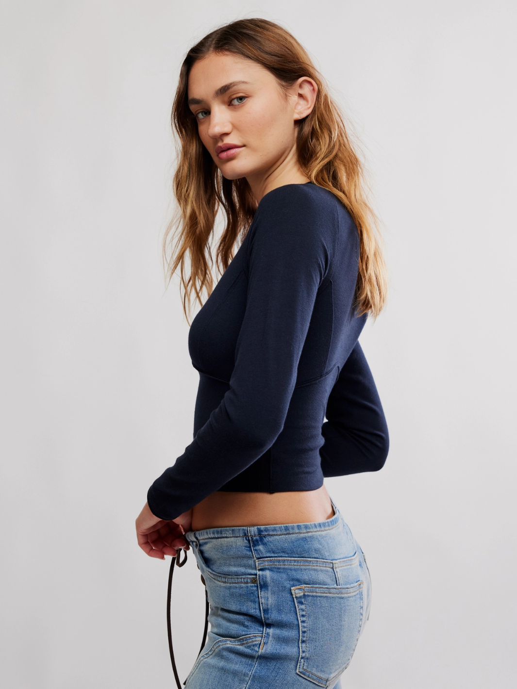 Model wearing navy Free People The Protagonist Long Sleeve top with denim jeans.