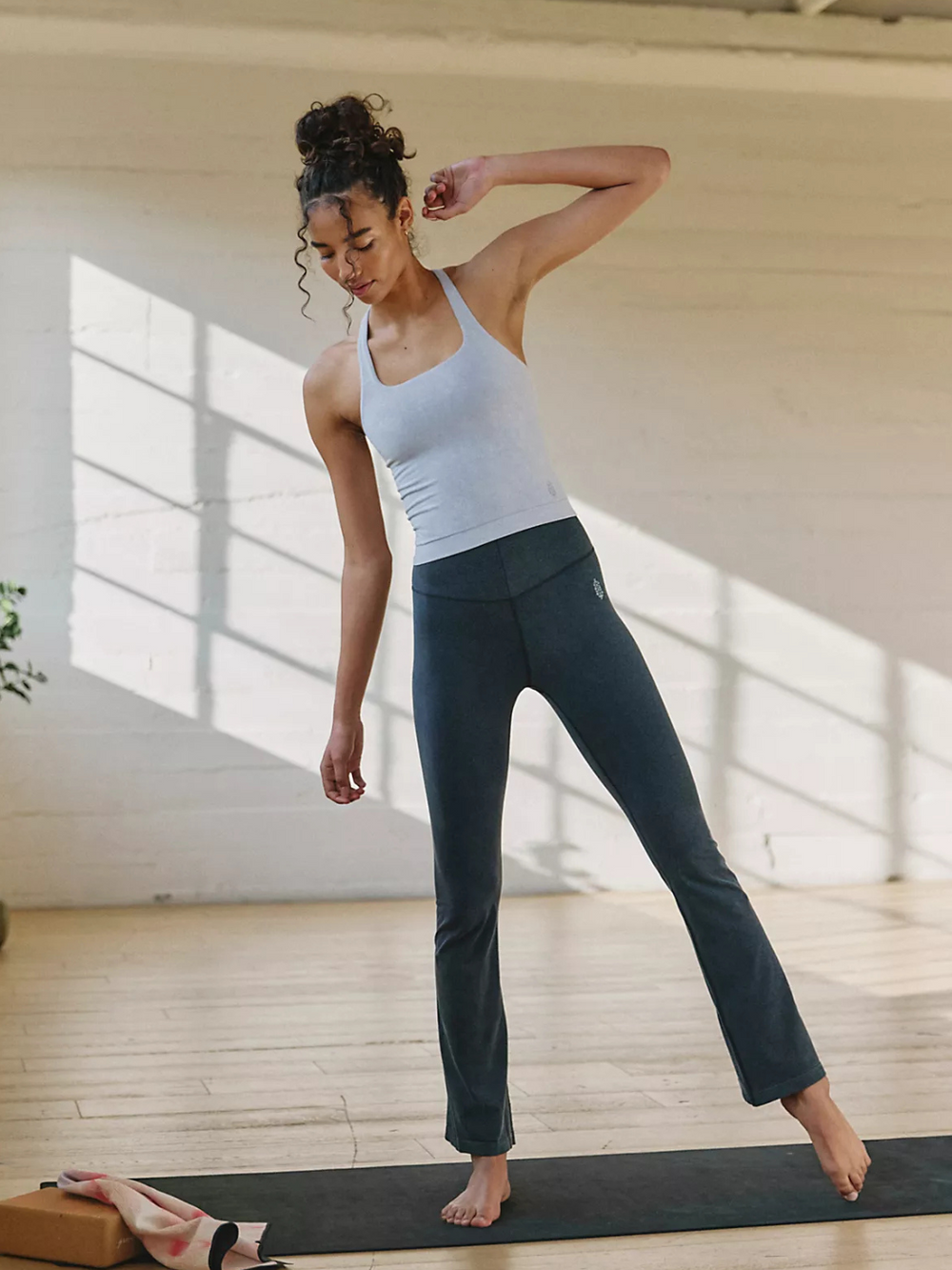 Stylish model showcases FREE PEOPLE - Go To Smooth Flare pants, perfect for versatile activewear looks.