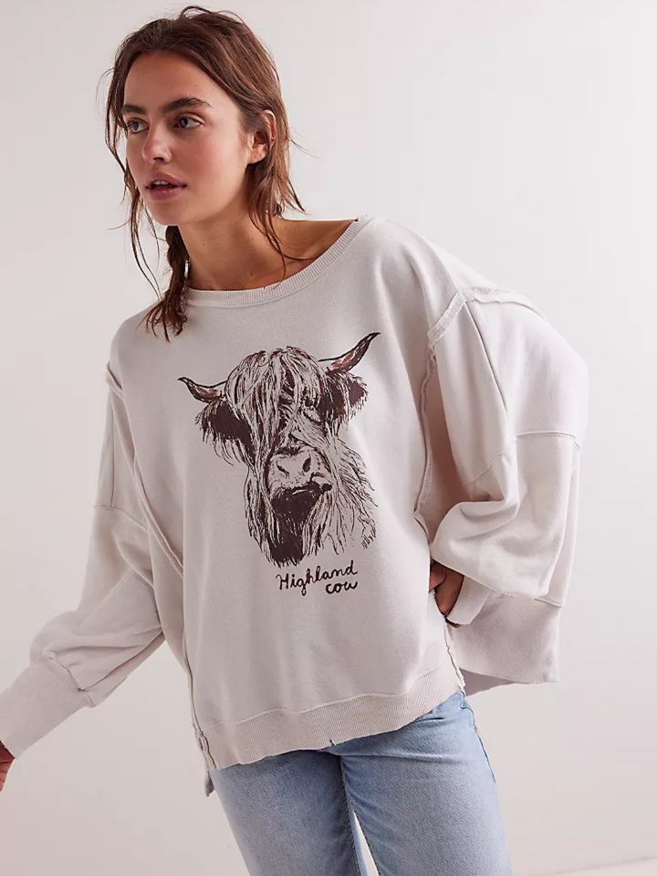 Relaxed fit model wearing the FREE PEOPLE - Graphic Camden Highland Cow long sleeve with vintage-inspired design.