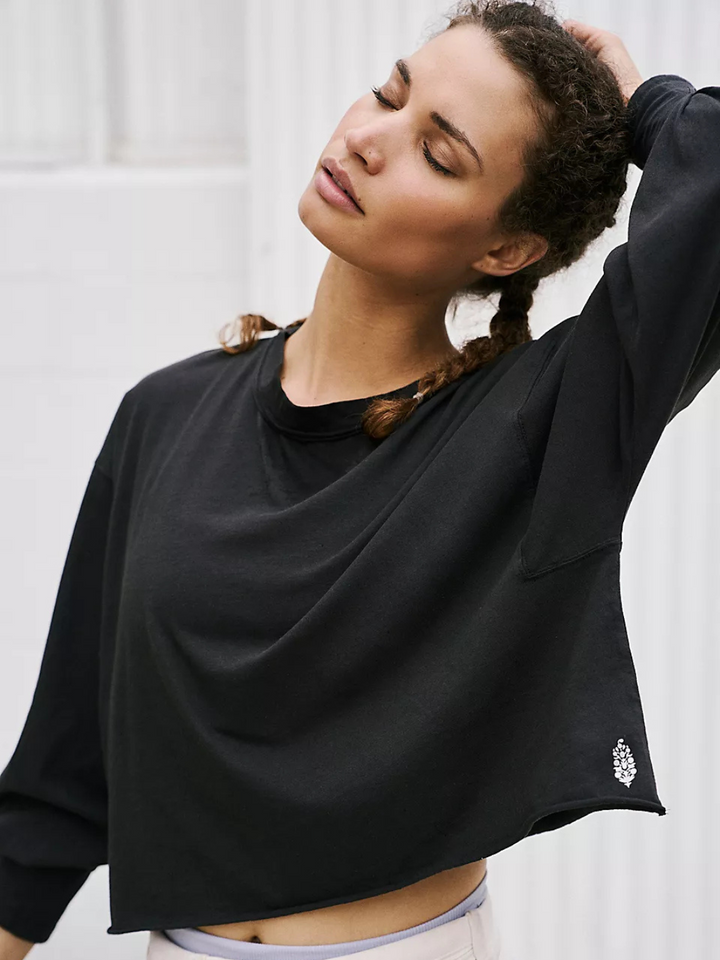Stylish model showcases the FREE PEOPLE - Inspire Layer long sleeve tee with a relaxed fit and raw-edge hem.