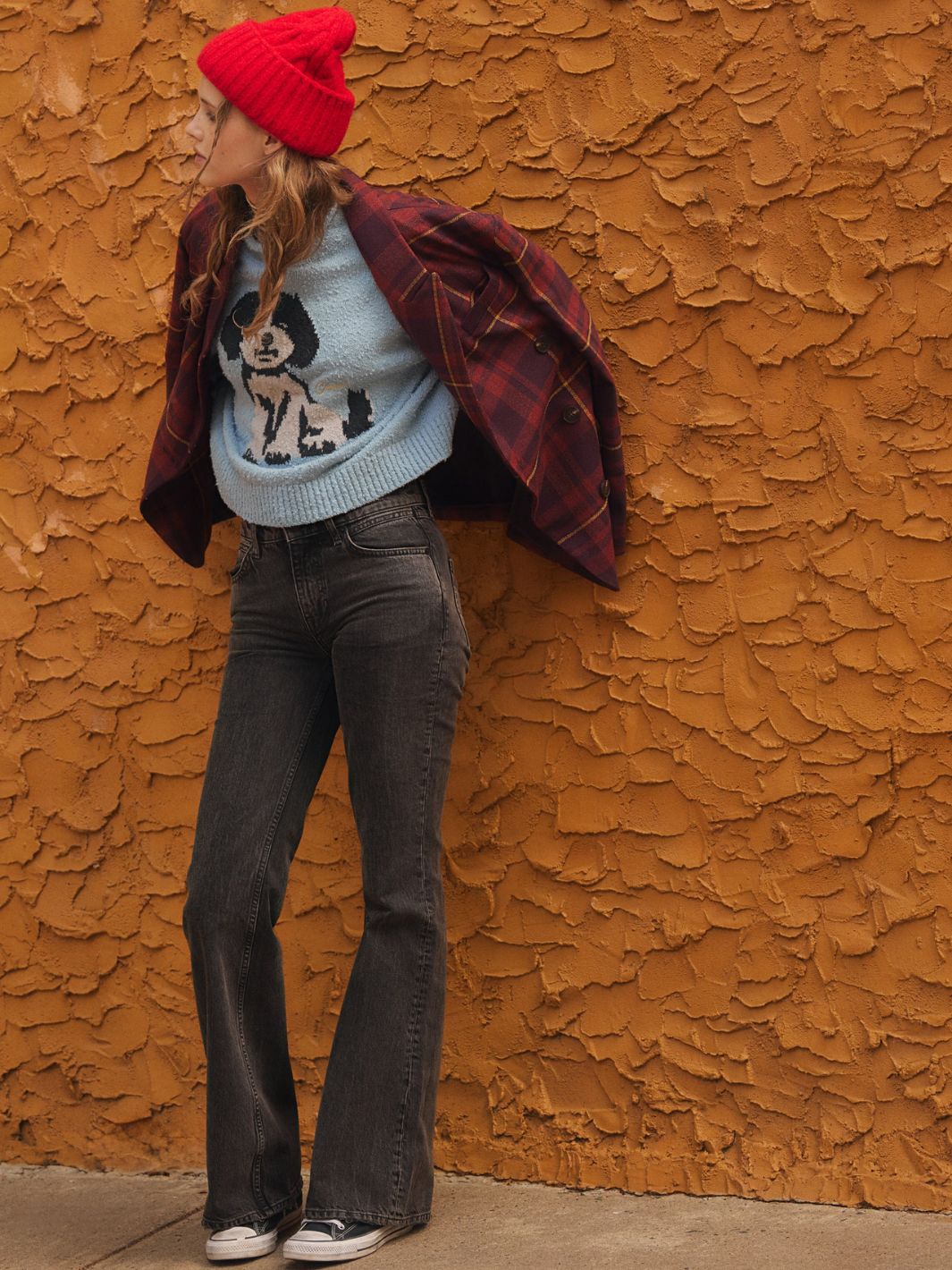 FREE PEOPLE Coast Line Beanie in red with chunky rib cuff on model against an orange textured wall.
