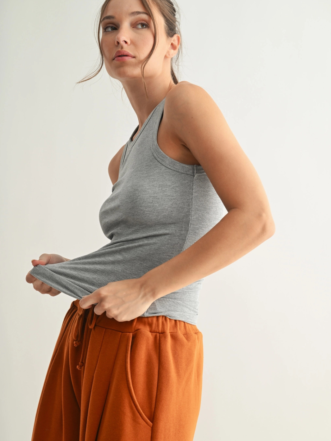 Go-To Micro Rib Tank Top on a model; heather gray, sleek body-hugging fit with rust-orange joggers.