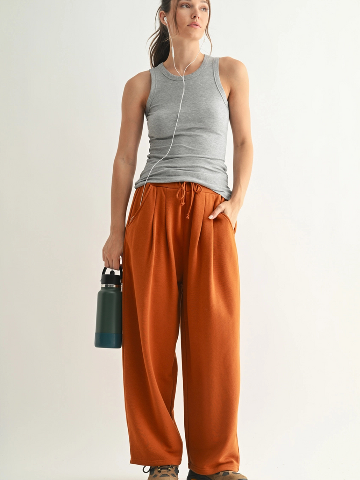 Go-To Micro Rib Tank Top on a gray-clad model with rust wide-leg pants, earphones, and a water bottle.