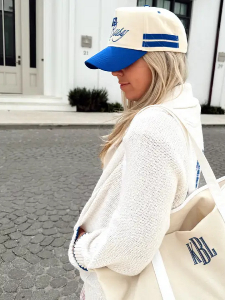 Stylish woman wearing the KENZKUSTOMZ - Booked and Busy Vintage Trucker Hat in royal blue. Perfect for summer vibes!